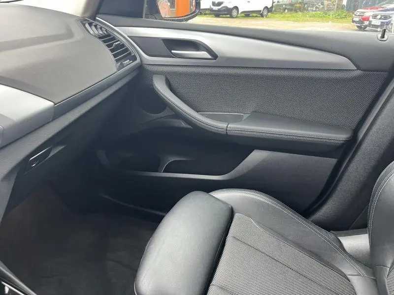 Intérieur côté passager du BMW X3 xDrive30e 2020 avec sellerie noire et panneau de porte en tissu et cuir anthracite.