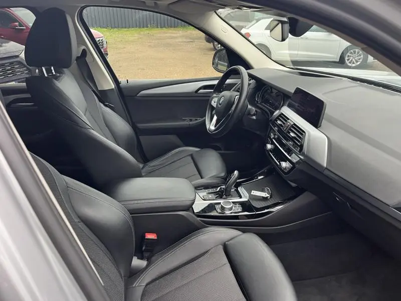 Intérieur noir de la BMW X3 xDrive30e 2020, vue côté conducteur avec tableau de bord et console centrale visibles.
