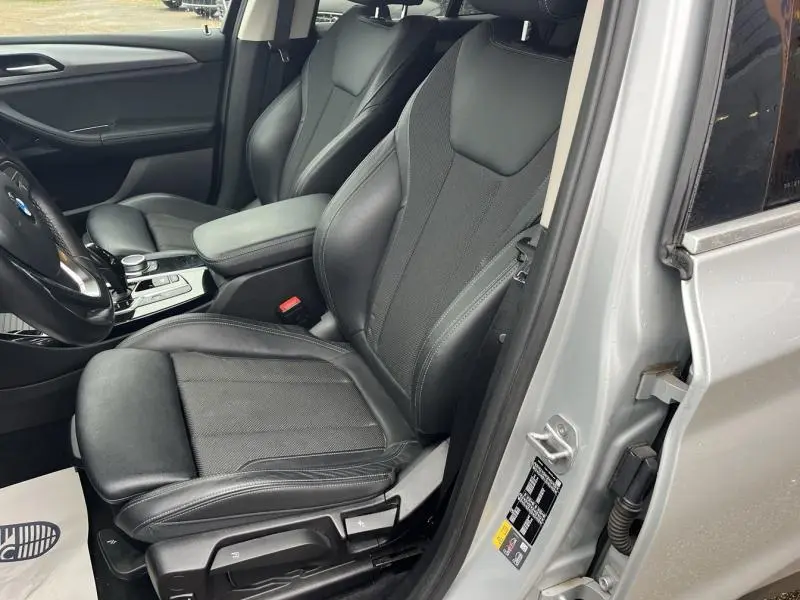 Vue intérieure côté conducteur du BMW X3 xDrive30e 2020 avec sièges en cuir noir et portière glaciersilber ouverte.