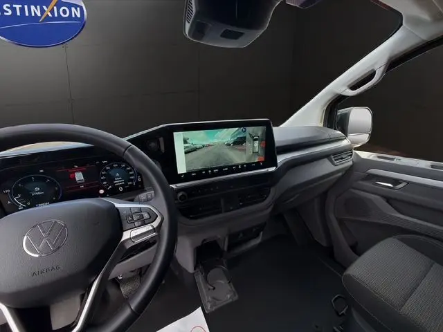 Vue intérieure côté conducteur du Volkswagen Transporter ProCab noir, avec tableau de bord numérique et écran tactile central affichant la caméra de recul.