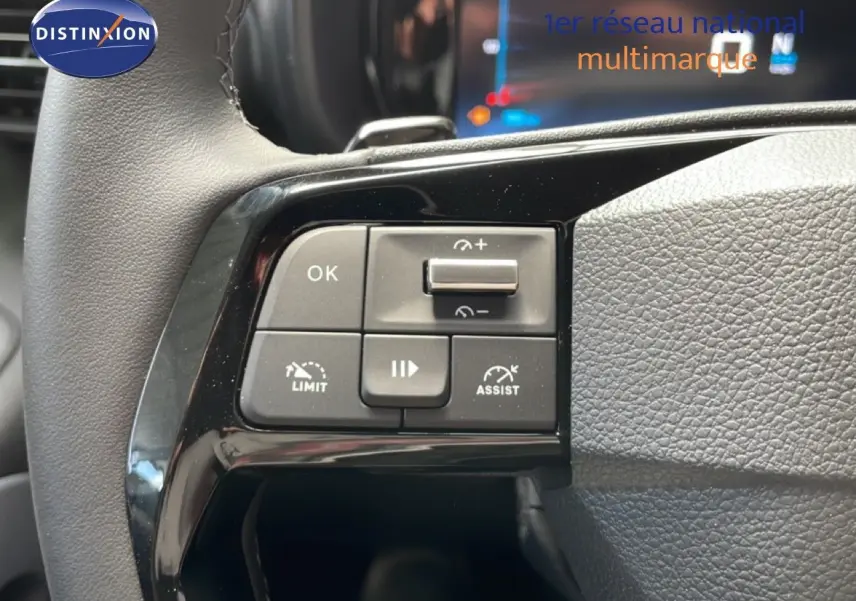 Gros plan sur les commandes au volant côté gauche du Citroën Berlingo gris Artense, avec boutons de limitation et assistance.