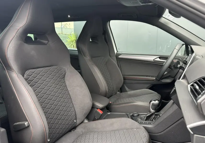 Intérieur du SEAT Tarraco 2024, vue côté droit sur sièges sport noirs avec surpiqûres rouges et volant cuir multifonction.