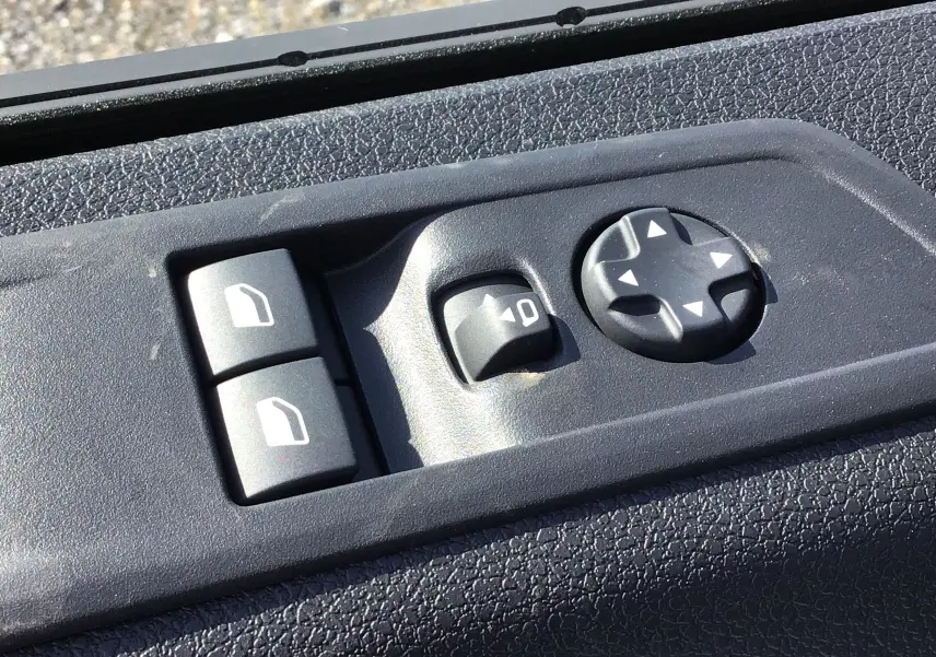 Gros plan sur les commandes de réglage des rétroviseurs et vitres du côté conducteur du Peugeot Expert Fourgon blanc 2025.