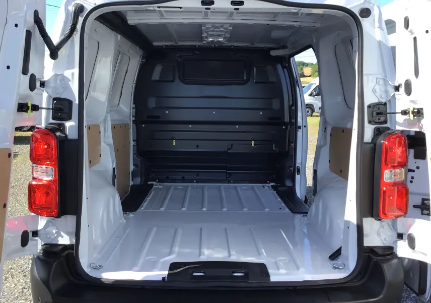 Vue arrière du fourgon blanc Peugeot Expert avec portes ouvertes, montrant l'espace de chargement vide et protégé.