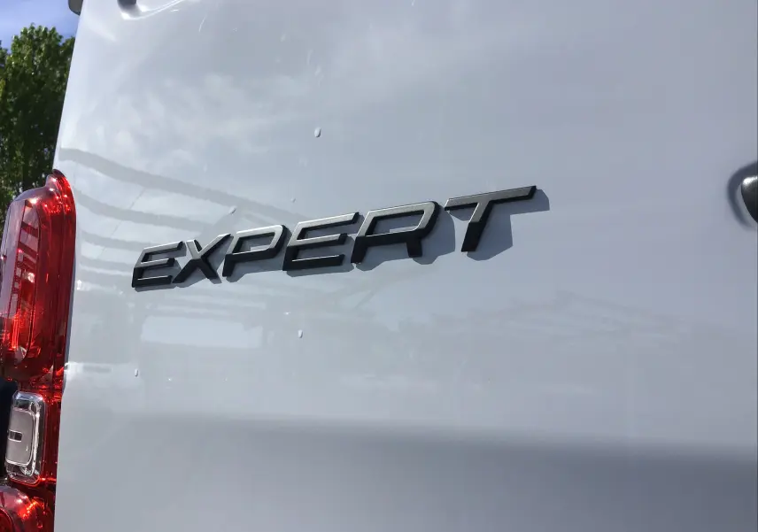 Gros plan sur l'arrière gauche blanc du Peugeot Expert Fourgon avec logo noir "EXPERT" et feu arrière rouge visible.
