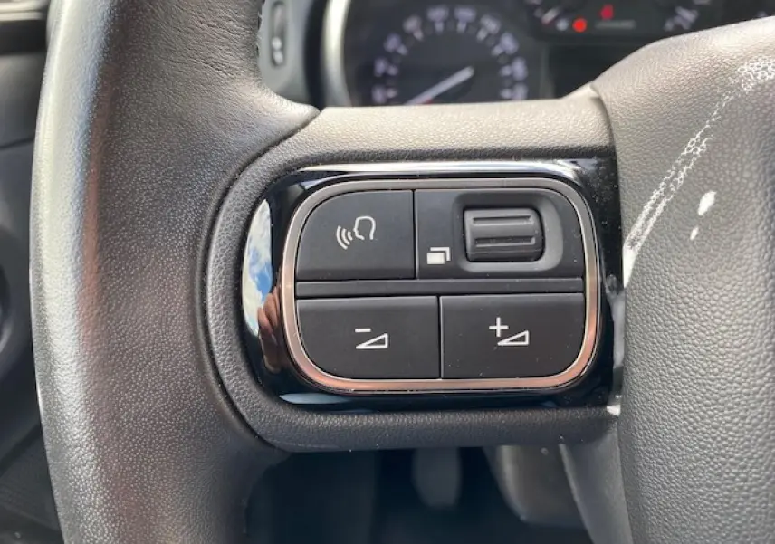 Gros plan sur les commandes de volume et de téléphone au volant d'une Citroën C3 2017, intérieur noir.