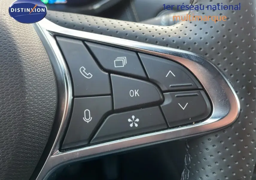Gros plan sur les commandes multifonctions du volant perforé noir du Renault Symbioz gris Cassiopée Métal.