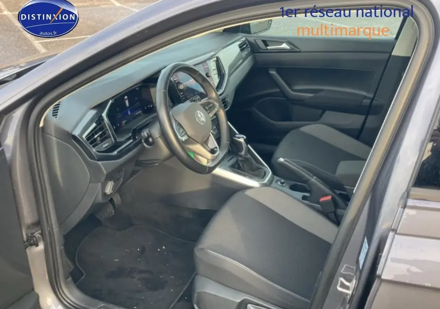 Vue intérieure côté conducteur de la Volkswagen Polo gris cendre 2025, avec tableau de bord digital et sièges tissu noir.