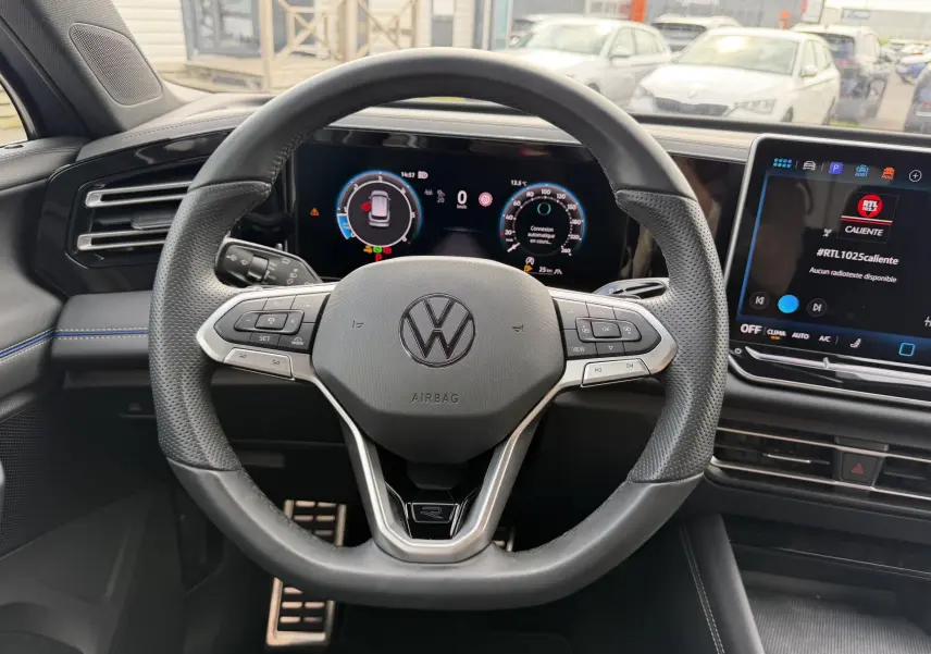 Vue centrée sur le volant cuir multifonction du Volkswagen Tiguan 2025 avec tableau de bord digital et écran tactile.