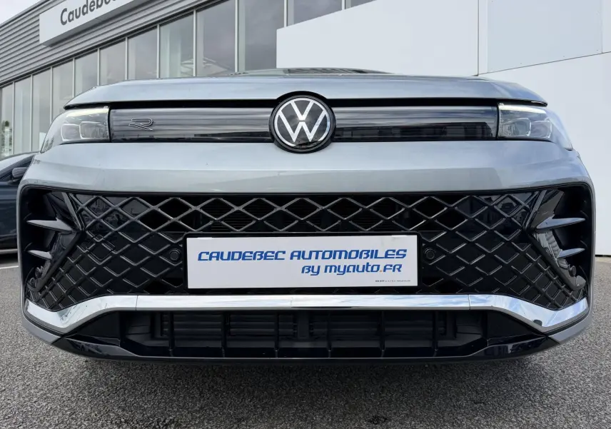 Vue frontale du Volkswagen Tiguan gris avec calandre noire à motif losange et logo VW central lumineux.