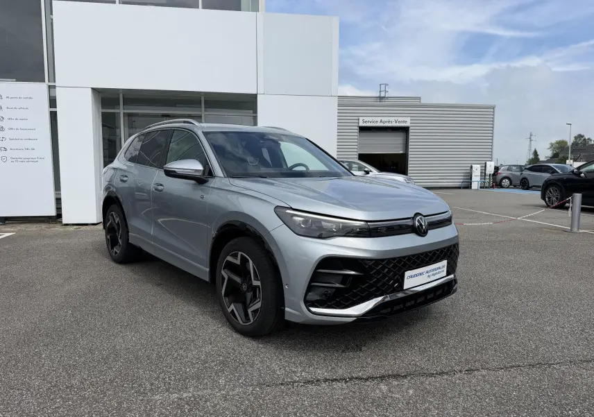 Volkswagen Tiguan gris en 3/4 avant droit, avec jantes noires et calandre au design sportif R-Line.