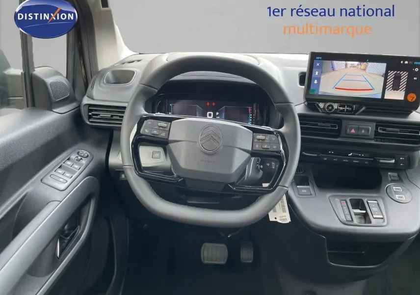 Vue intérieure frontale du poste de conduite du Citroën Berlingo noir, avec volant multifonction et écran tactile affichant la caméra de recul.