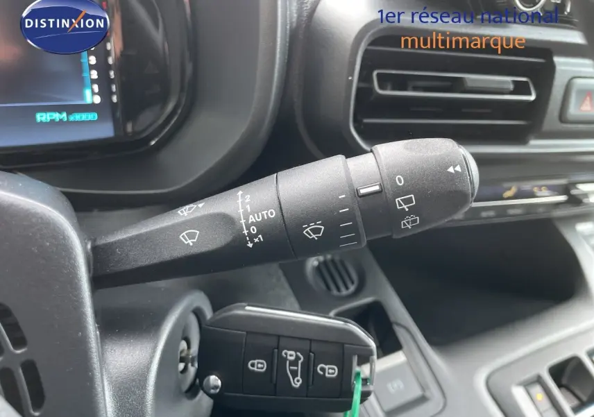 Gros plan sur la commande d’essuie-glace et la clé insérée dans le contacteur d’un Citroën Berlingo noir, intérieur tableau de bord.