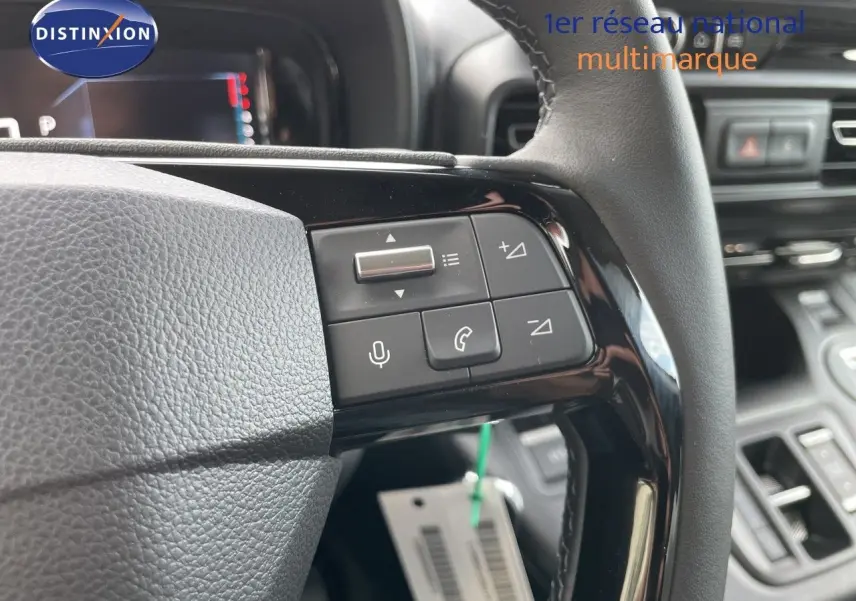 Gros plan sur les commandes au volant du Citroën Berlingo 2026, finition noire avec boutons multifonctions et tableau de bord en arrière-plan.