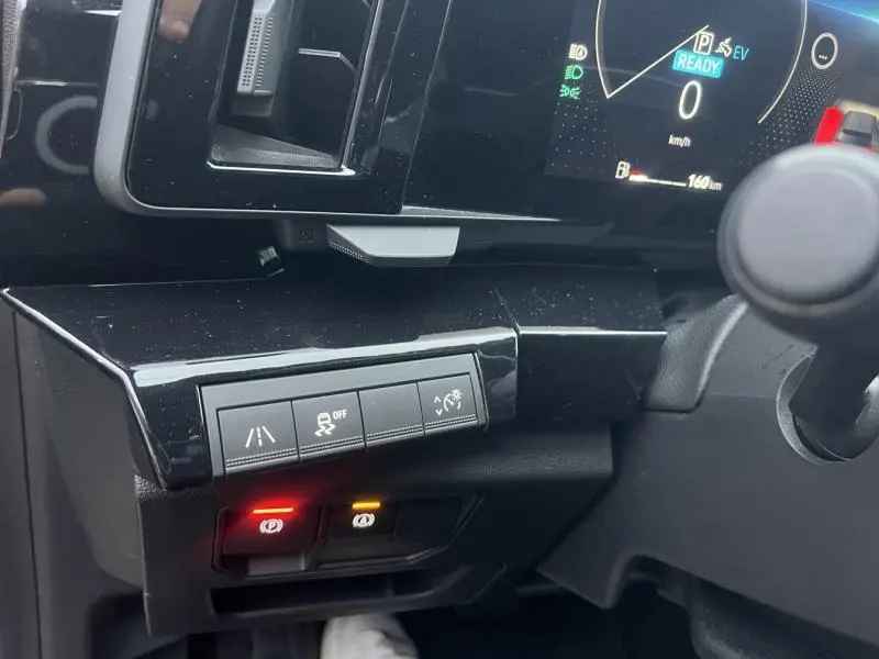 Détail du tableau de bord côté gauche du Renault Austral blanc 2023 avec commandes d'assistance et écran numérique allumé.