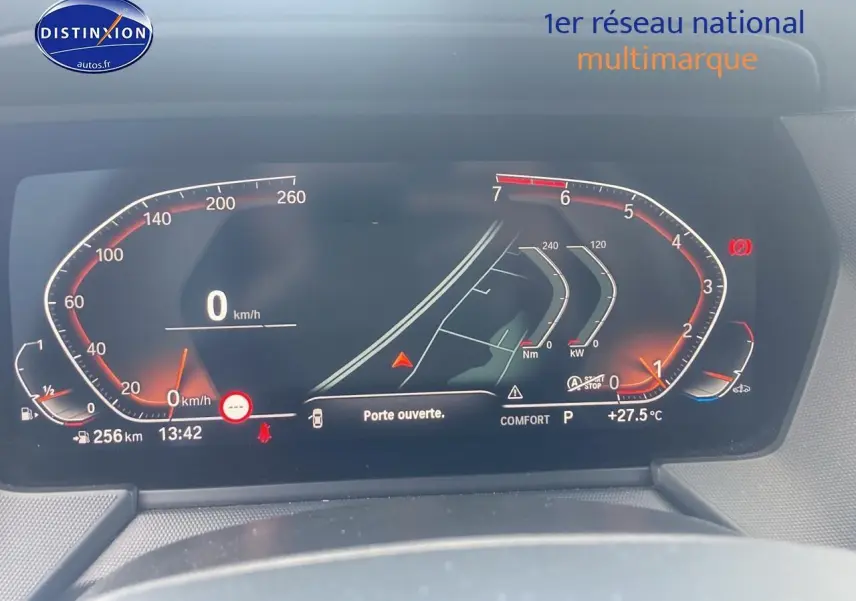 Tableau de bord numérique de BMW Série 1 (F40) 118i 2023 affichant vitesse, température et alertes, vue frontale rapprochée.