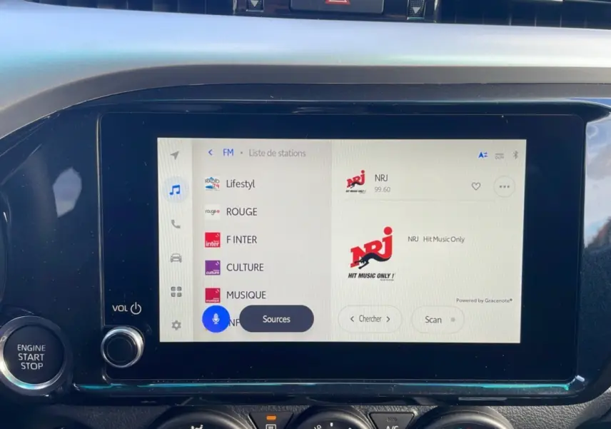Écran tactile central du Toyota Hilux 2025 blanc, affichant la liste des stations radio FM avec NRJ sélectionné.