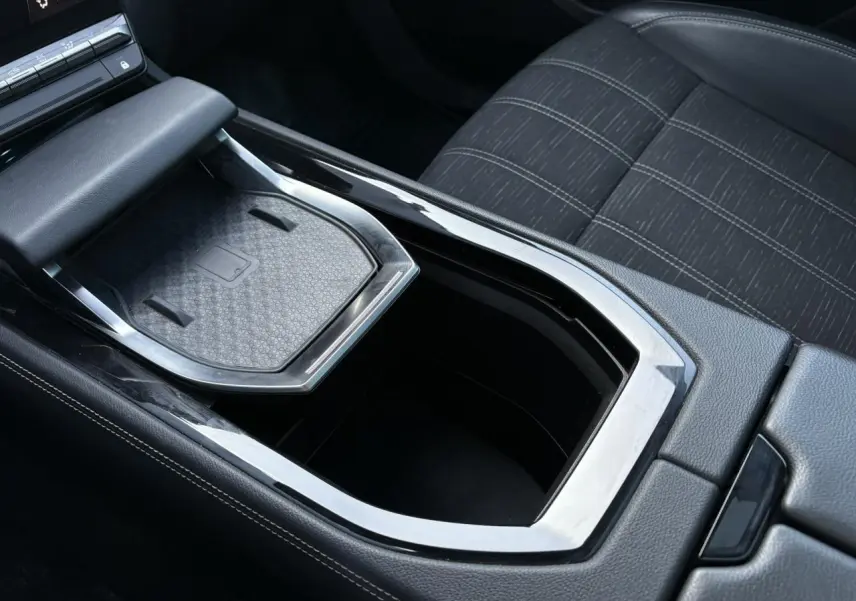 Gros plan sur la console centrale du Renault Austral E-Tech, montrant le chargeur sans fil et la sellerie tissu gris.