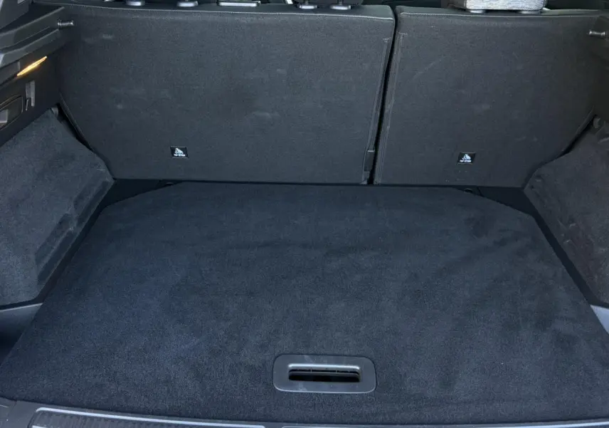 Coffre ouvert vu de l'arrière du Renault Austral E-Tech Full Hybrid 2024, intérieur noir avec sièges rabattus.