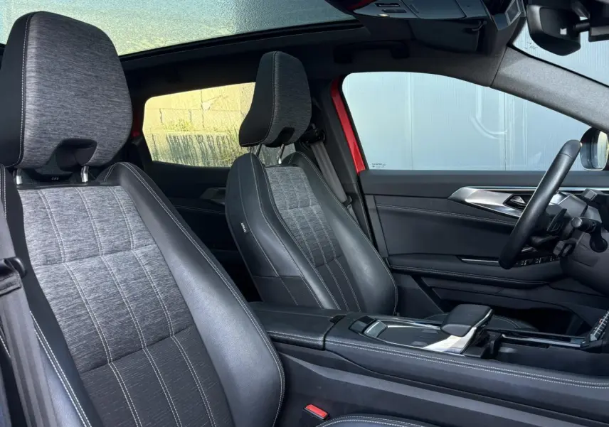 Intérieur du Renault Austral E-Tech 2024 montrant les sièges avant en simili-cuir gris et toit panoramique ouvert.