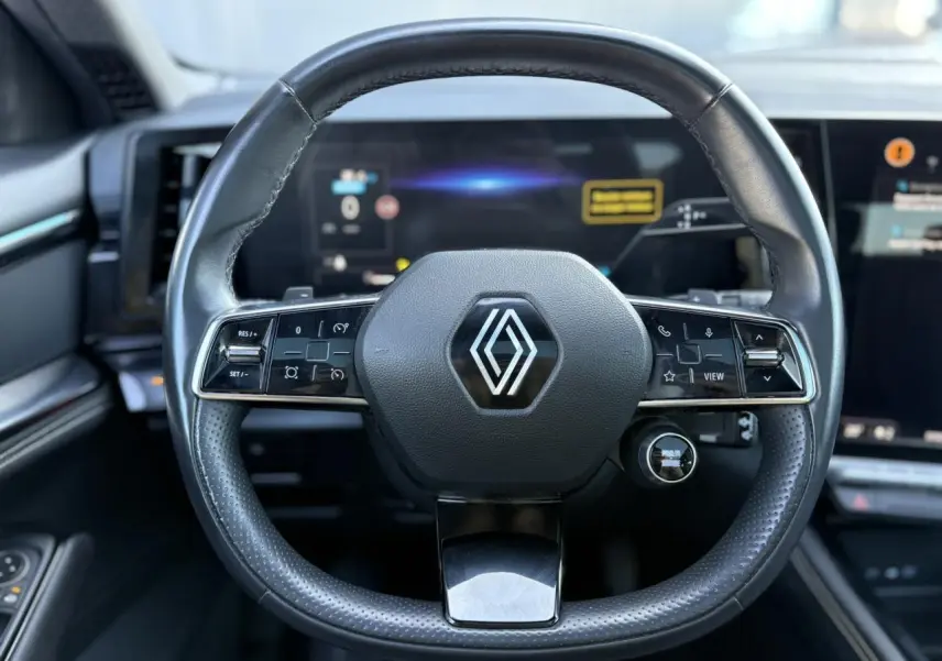 Volant cuir noir Renault avec commandes intégrées, vue frontale sur le tableau de bord numérique du Renault Austral 2024.