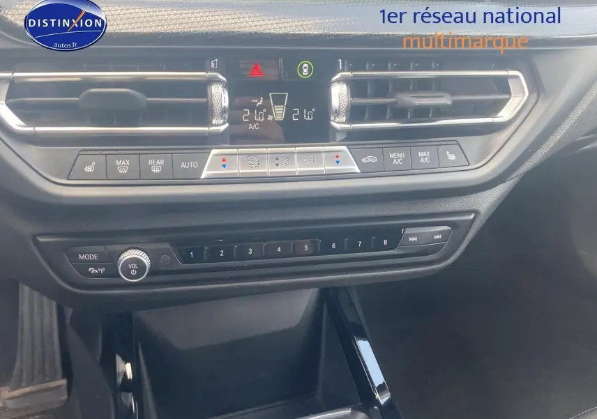 Tableau de bord et console centrale de BMW Série 1 noire, avec commandes climatisation et audio visibles en gros plan.