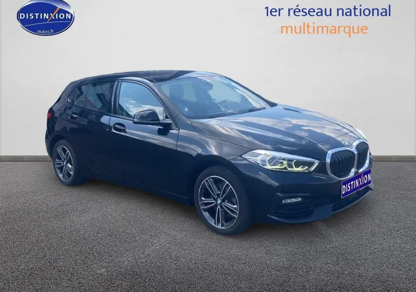 BMW Série 1 noire vue en 3/4 avant droit avec phares LED allumés et jantes alliage 17 pouces double rayons.