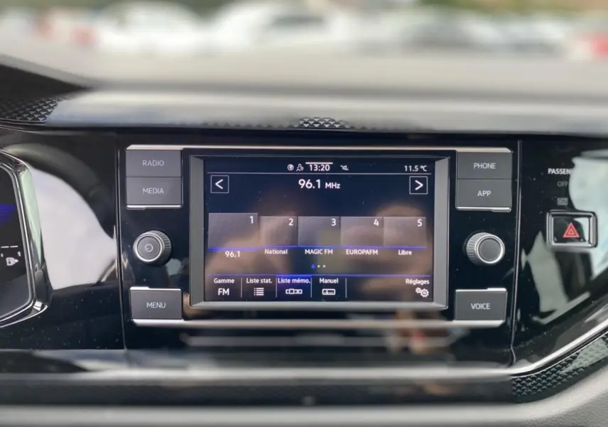 Écran tactile central 8 pouces du Volkswagen Taigo 2022 affichant la radio FM, entouré de commandes noires brillantes.