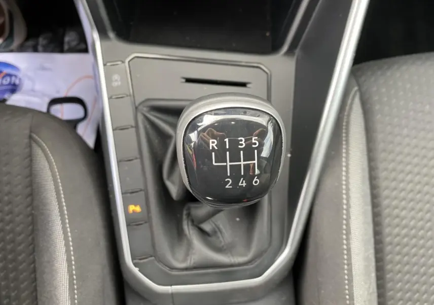 Gros plan sur le levier de vitesses manuel noir du Volkswagen Taigo 2022, entouré de sièges en tissu gris.