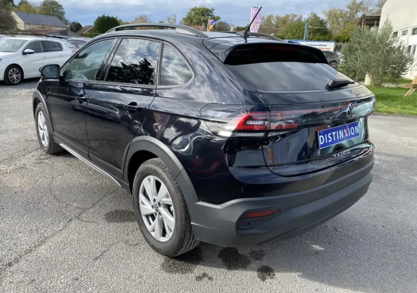 Vue 3/4 arrière droite d'un Volkswagen Taigo noir intense avec feux arrière allongés et jantes argentées.
