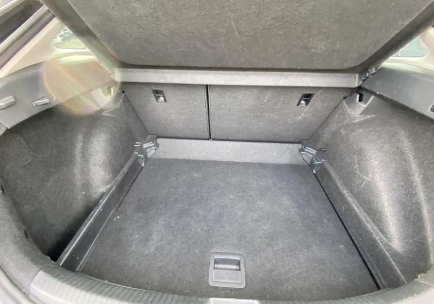 Coffre ouvert en vue plongeante d'un Volkswagen Taigo noir intense, montrant un espace de chargement propre et vide.