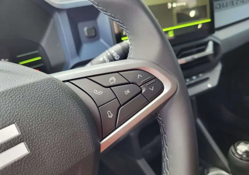 Gros plan sur les commandes au volant du Dacia Duster 2025, version TCE 130 4X2 Journey, avec finition noire et surpiqûres.