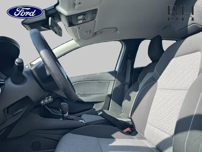 Vue intérieure côté gauche de la Renault Clio 1.6 E-Tech hybride 2023 avec sièges tissu gris et volant multifonction.