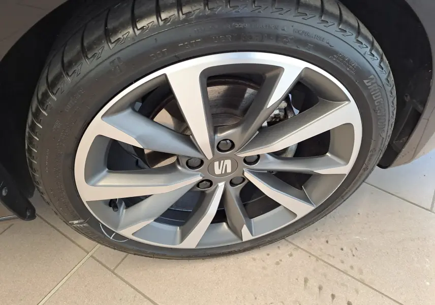 Gros plan sur la jante alliage grise au design moderne du SEAT LEON 1.5 eTSI Hybrid 2024 noir minuit.