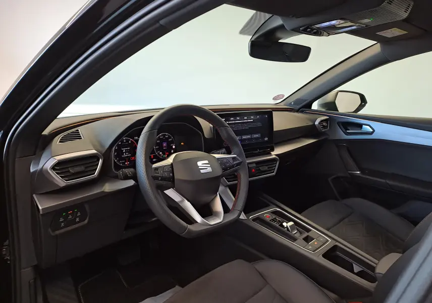 Vue intérieure côté conducteur de la SEAT LEON 1.5 eTSI Hybrid 2024 en Noir Minuit, avec tableau de bord numérique et écran tactile central.