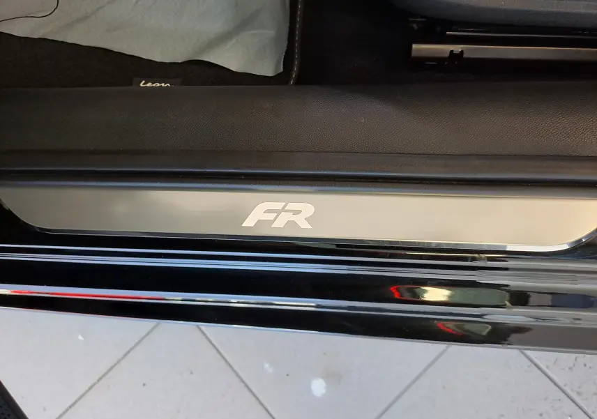 Gros plan sur la plaque de seuil de porte FR du SEAT Leon 1.5 eTSI Hybrid noir minuit, côté gauche, finition 2024.