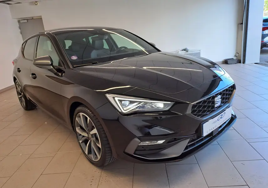 SEAT Leon 1.5 eTSI Hybrid 2024 en noir minuit, vue 3/4 avant mettant en valeur les phares LED et la calandre distinctive.