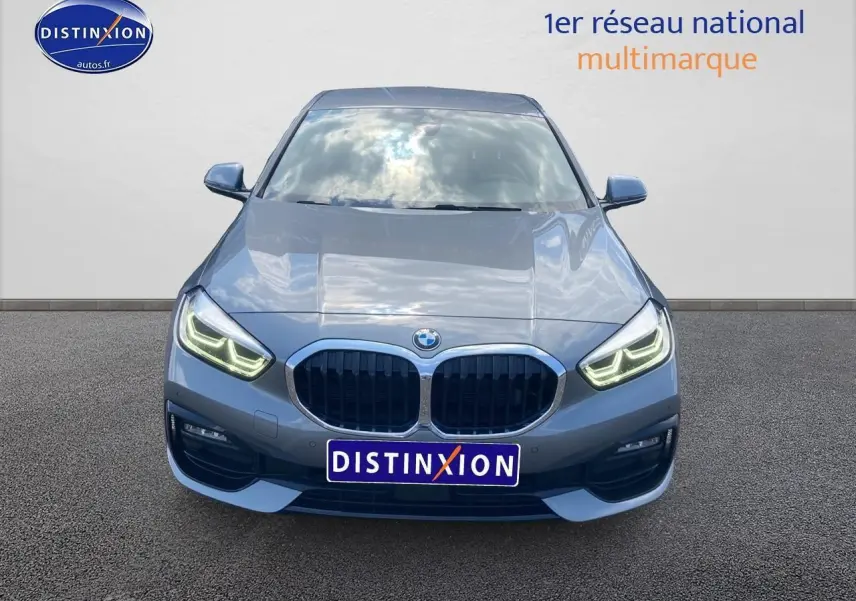 Vue frontale d'une BMW Série 1 gris foncé avec phares LED allumés sur fond neutre.