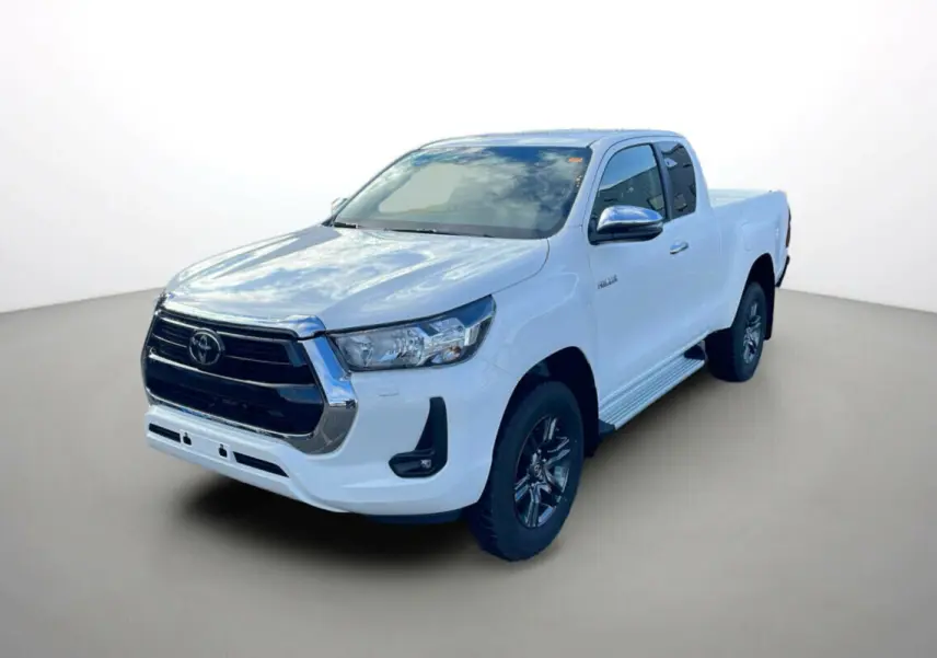 Toyota Hilux 4x4 blanc pur en 3/4 avant droit, avec calandre noire et jantes foncées distinctives.