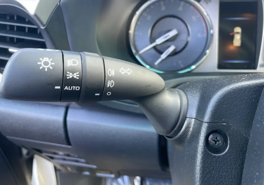 Gros plan sur la commande des phares du Toyota Hilux 2025, tableau de bord et compteur en arrière-plan.