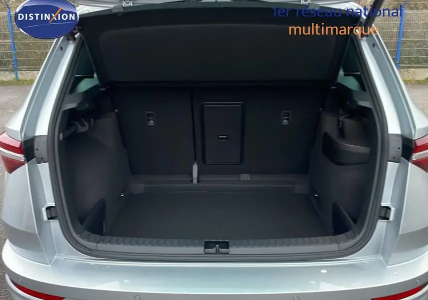 Coffre ouvert vu de l'arrière d'un Skoda Karoq gris argent métal, montrant l'espace de chargement vide.