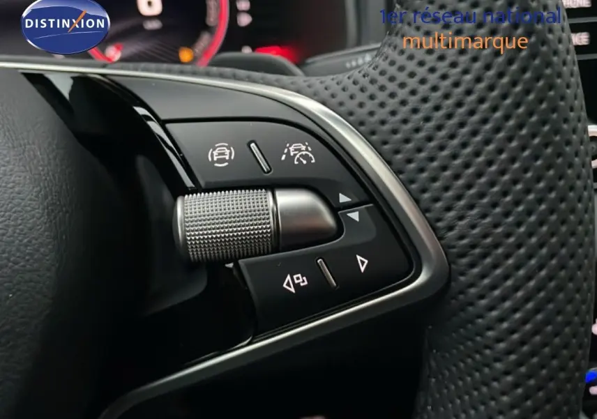 Gros plan sur les commandes au volant perforé d'une Skoda Karoq gris argent 2025, version Sportline essence.