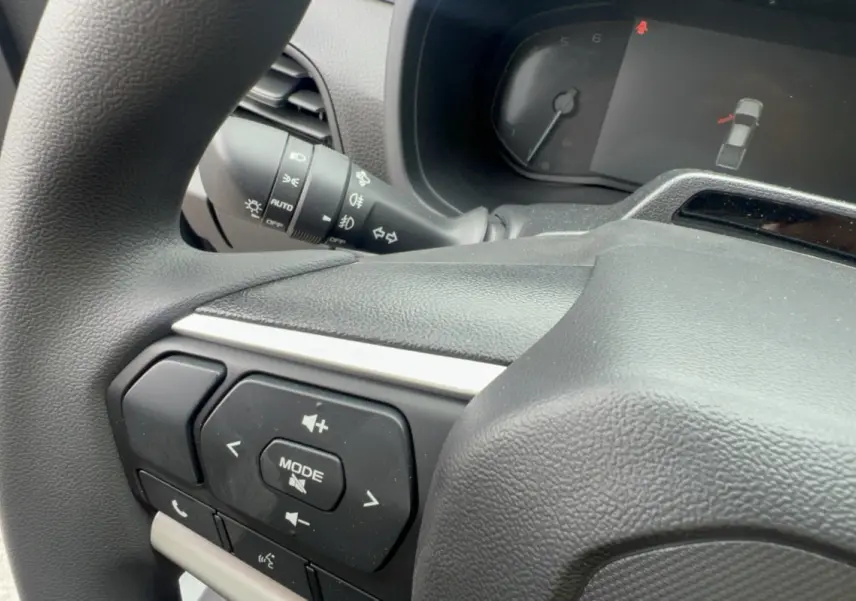 Gros plan sur le volant multifonctions noir de l'Isuzu D-MAX 2026 avec commandes audio et affichage tableau de bord.
