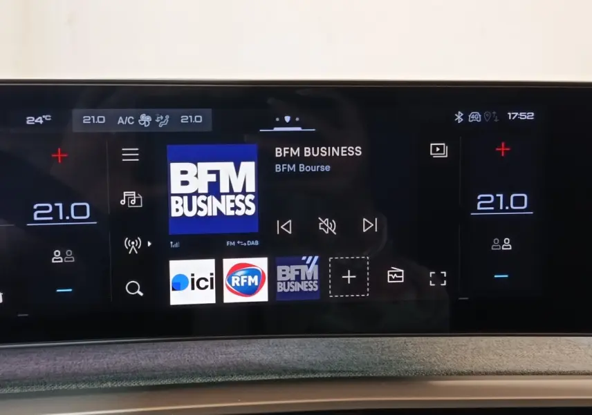 Écran tactile central du Peugeot 5008 gris clair 2026 affichant la radio BFM Business et réglages climatisation à 21°C.