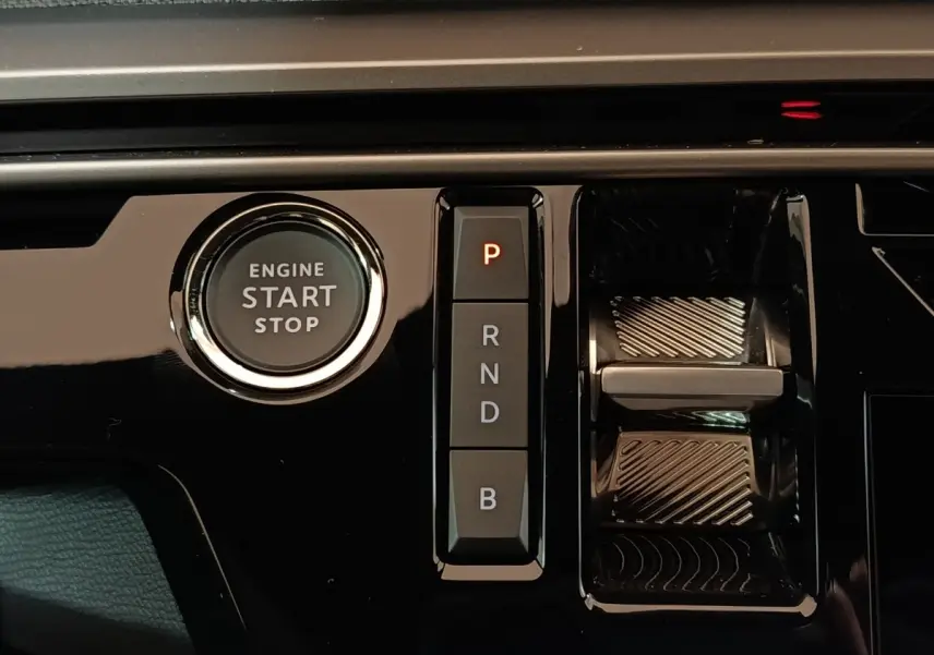 Gros plan sur la console centrale noire brillante du Peugeot 5008 gris clair, avec bouton start/stop et commandes de boîte automatique.