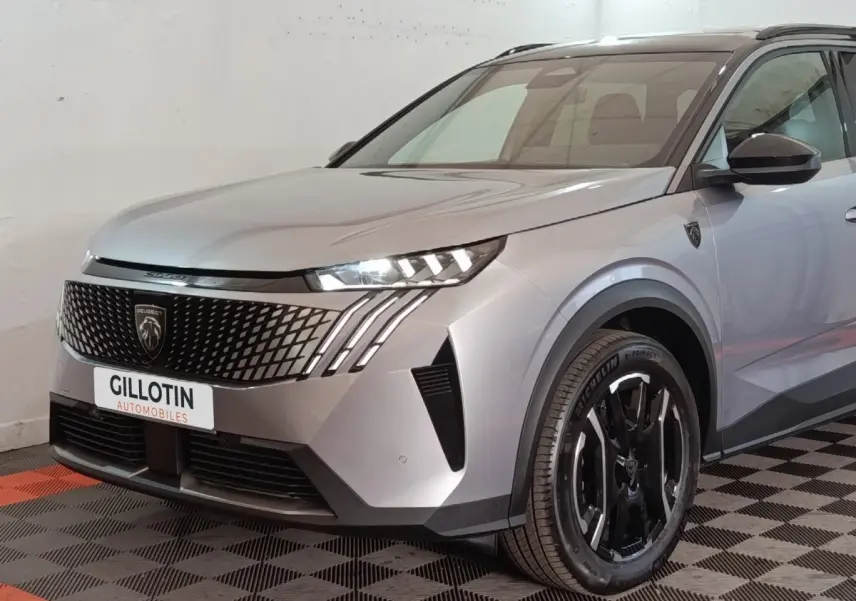 Vue 3/4 avant droite d'un Peugeot 5008 gris clair avec calandre noire et phares LED distinctifs.