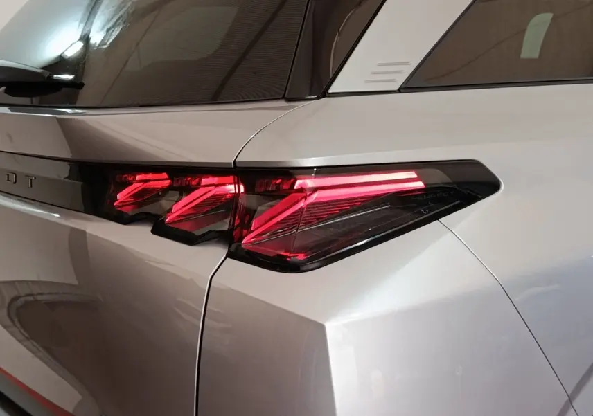 Gros plan sur le feu arrière droit rouge vif du Peugeot 5008 gris clair, soulignant la ligne anguleuse de la carrosserie.
