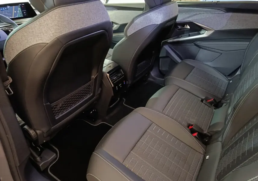 Vue intérieure arrière côté droit du Peugeot 5008 gris clair, montrant les sièges et la console centrale avec commandes climatisation.
