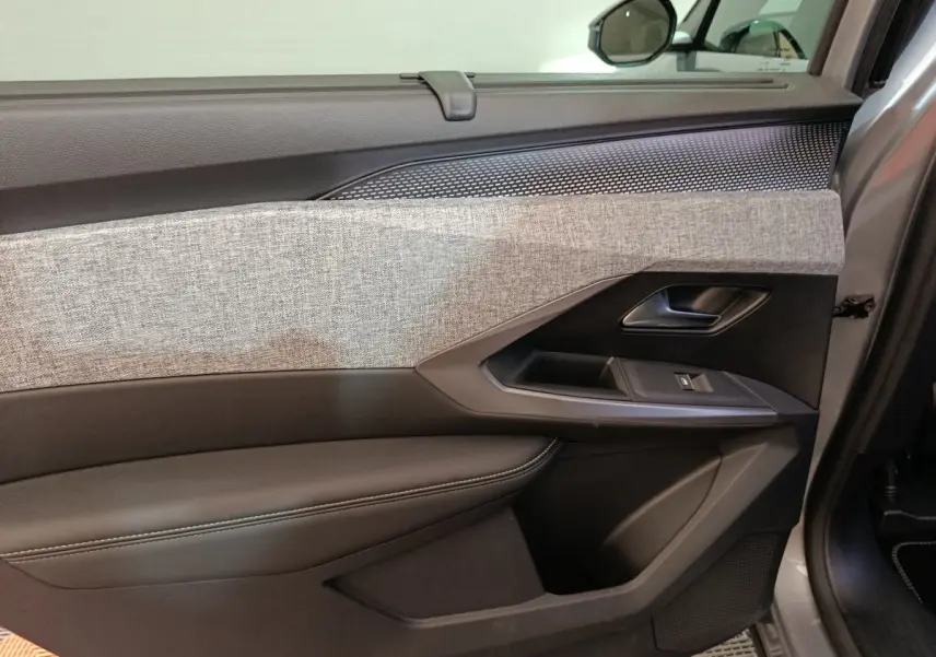 Vue rapprochée de la porte avant droite du Peugeot 5008 gris clair, avec habillage tissu clair et garnitures noires.