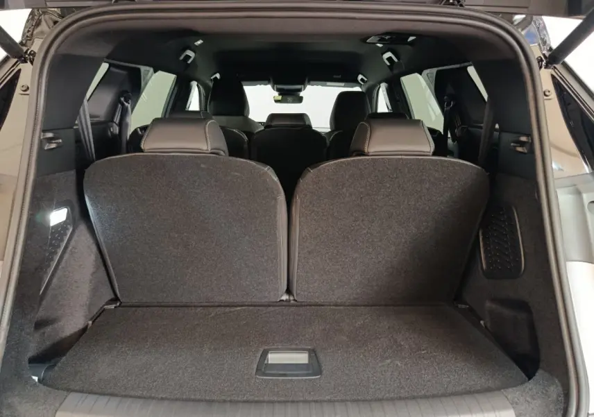 Coffre ouvert vu de l'arrière d'un Peugeot 5008 gris clair, sièges de troisième rangée relevés.